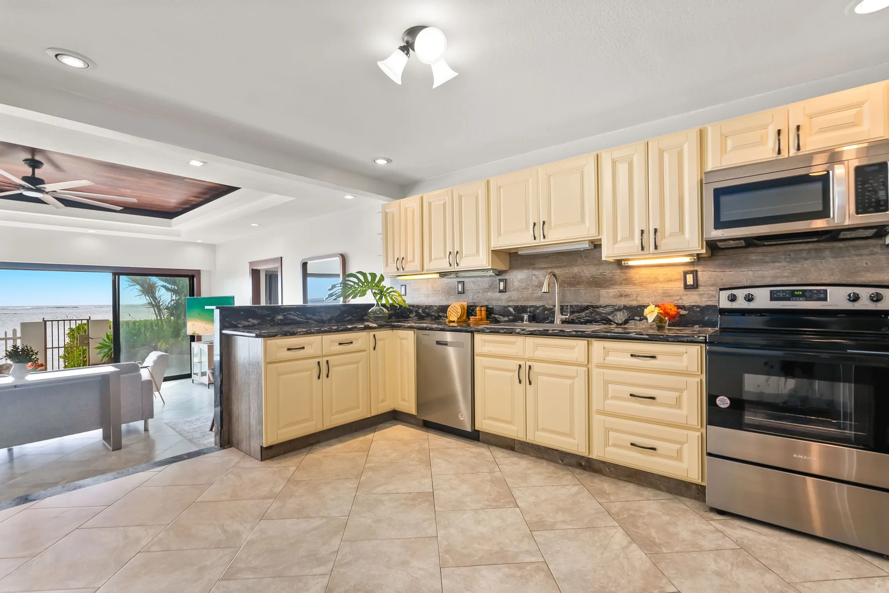 A spacious kitchen with light cabinets, dark countertops, and stainless steel appliances.