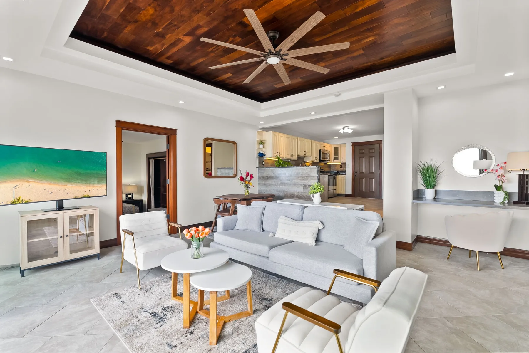 A bright living room with seating around a coffee table and an open kitchen beyond.