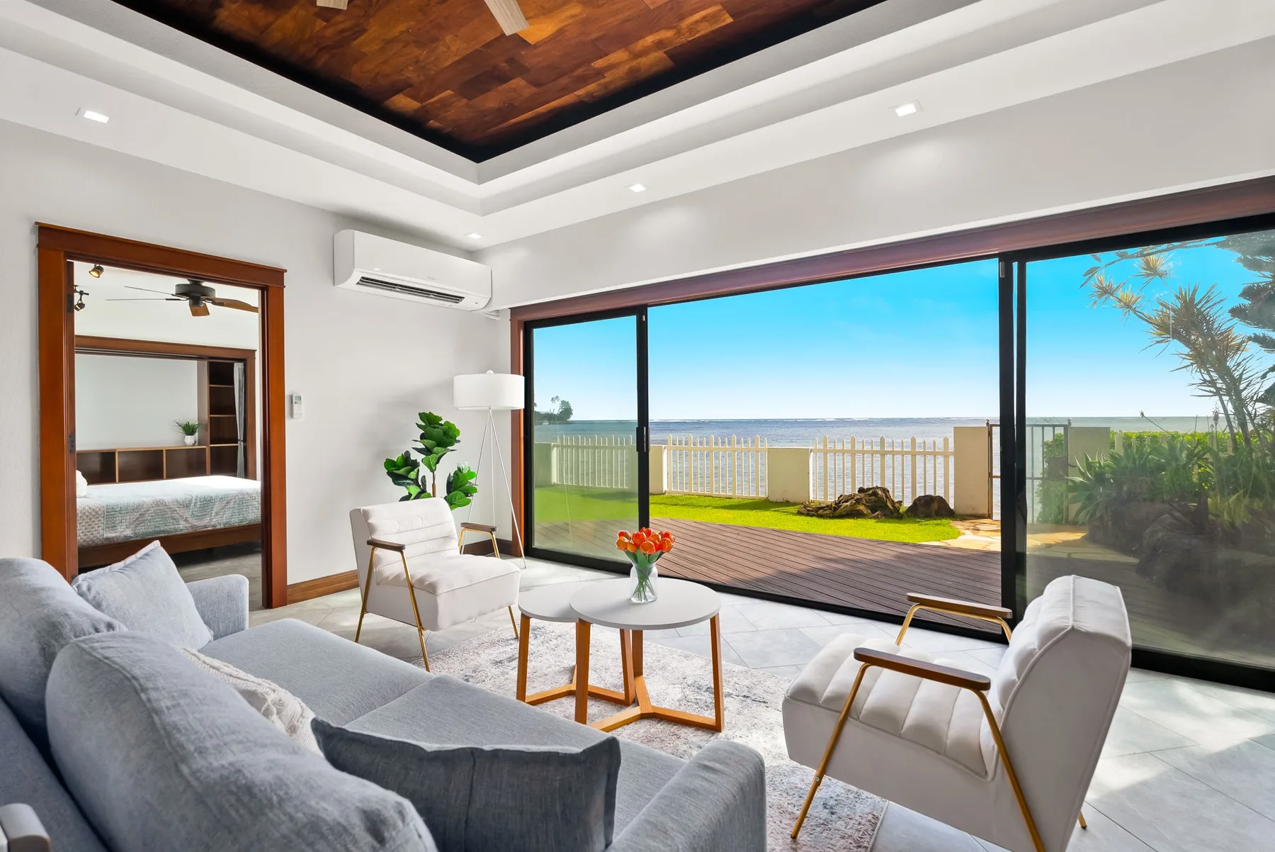 A bright living room opens onto a deck through wide glass doors.