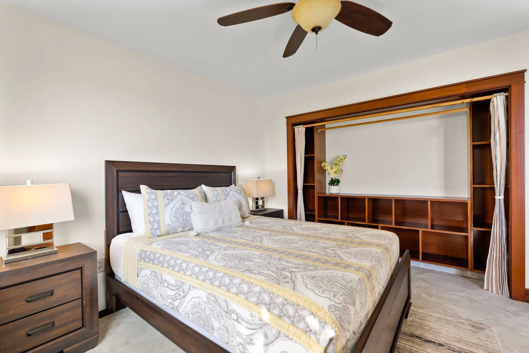 A bedroom with a large bed and built-in wooden shelving along the wall.