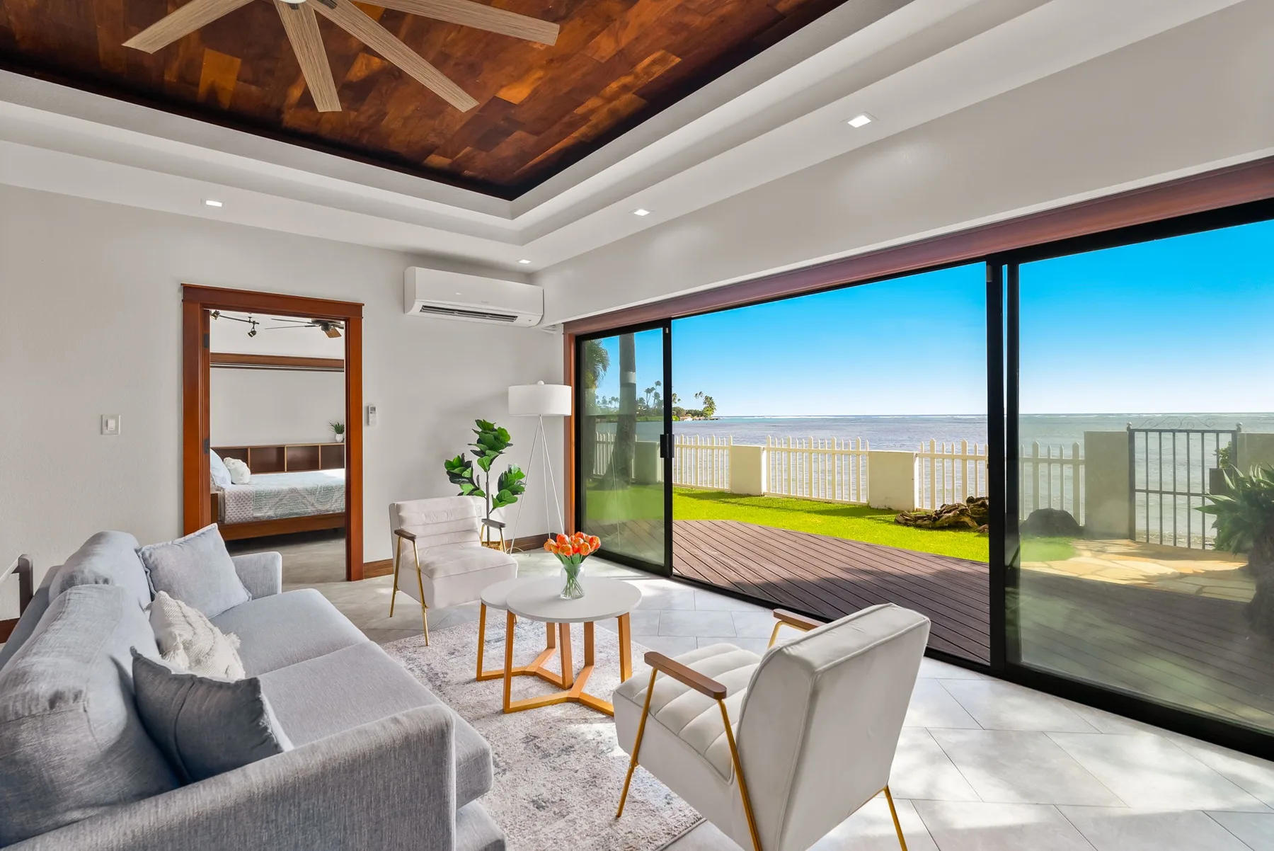 A bright living room opens onto a deck with a wide view of the water.