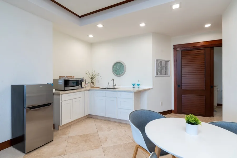 A bright kitchen and dining area with white cabinets and a round table.