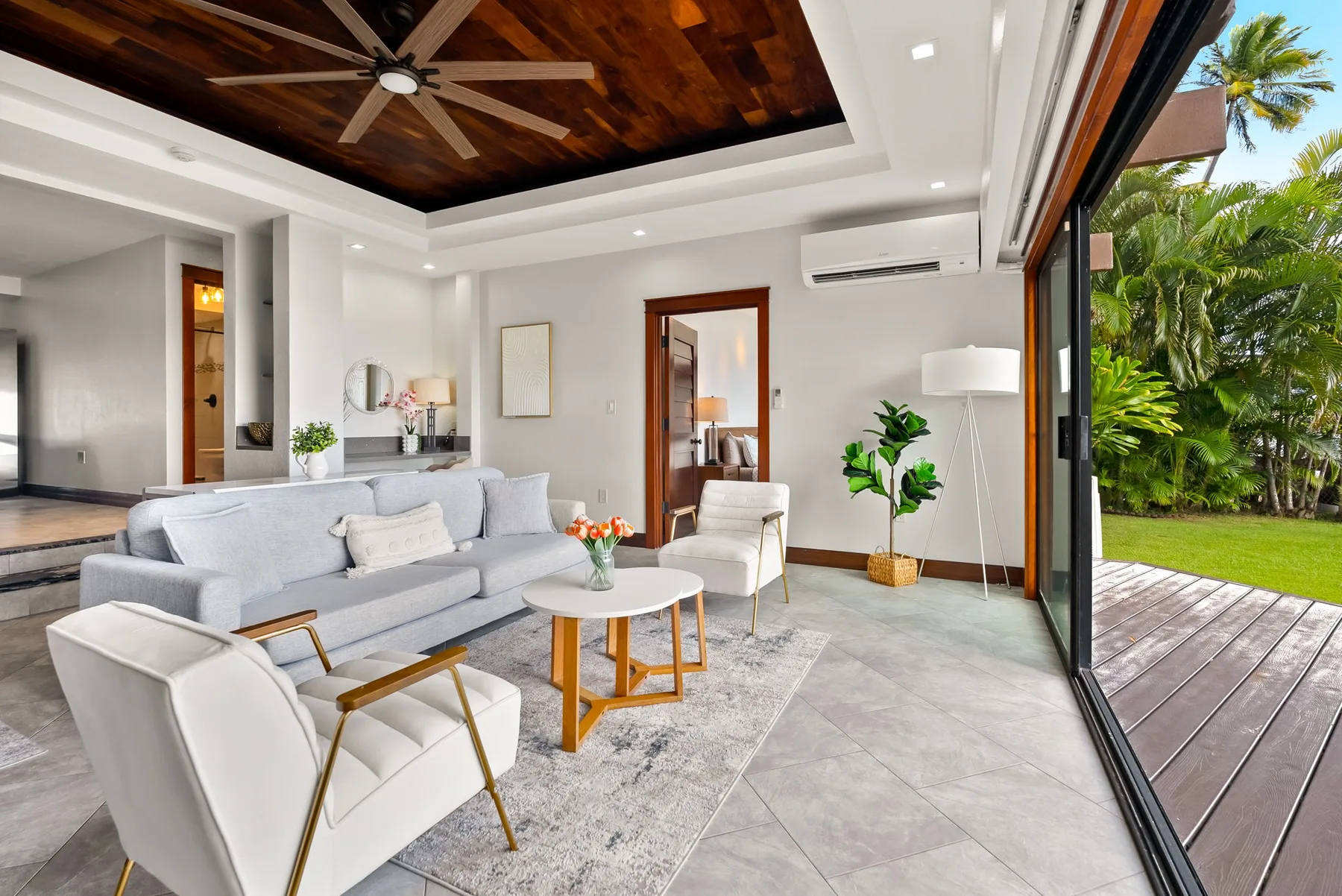 A bright living room with seating, a coffee table, and sliding glass doors opening to a patio.