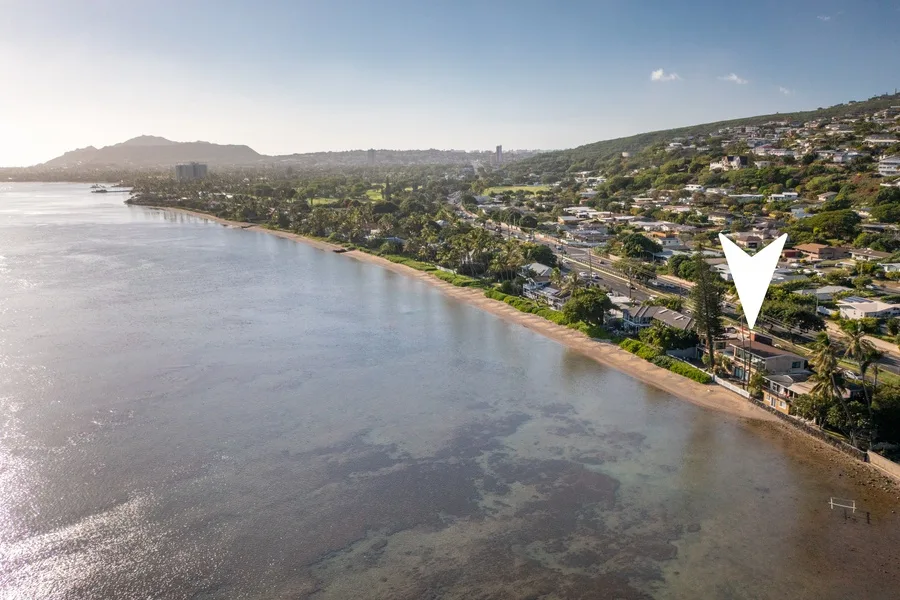 Aerial view of a coastal shoreline with houses along the hillside.