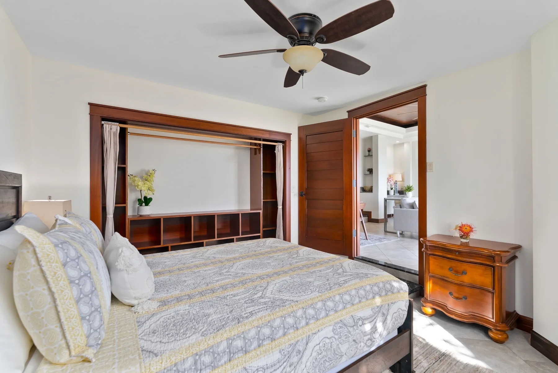 A bedroom with a bed, built-in shelving, and a ceiling fan.
