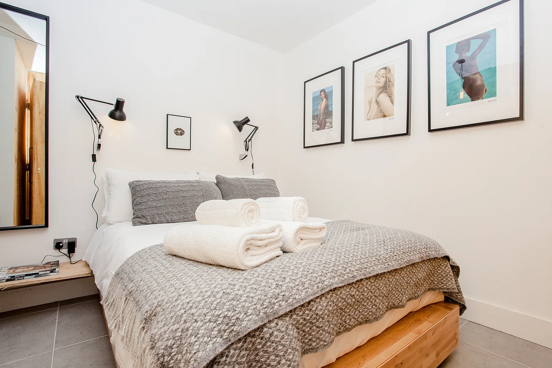 A bedroom with a neatly made bed and framed artwork on the walls.