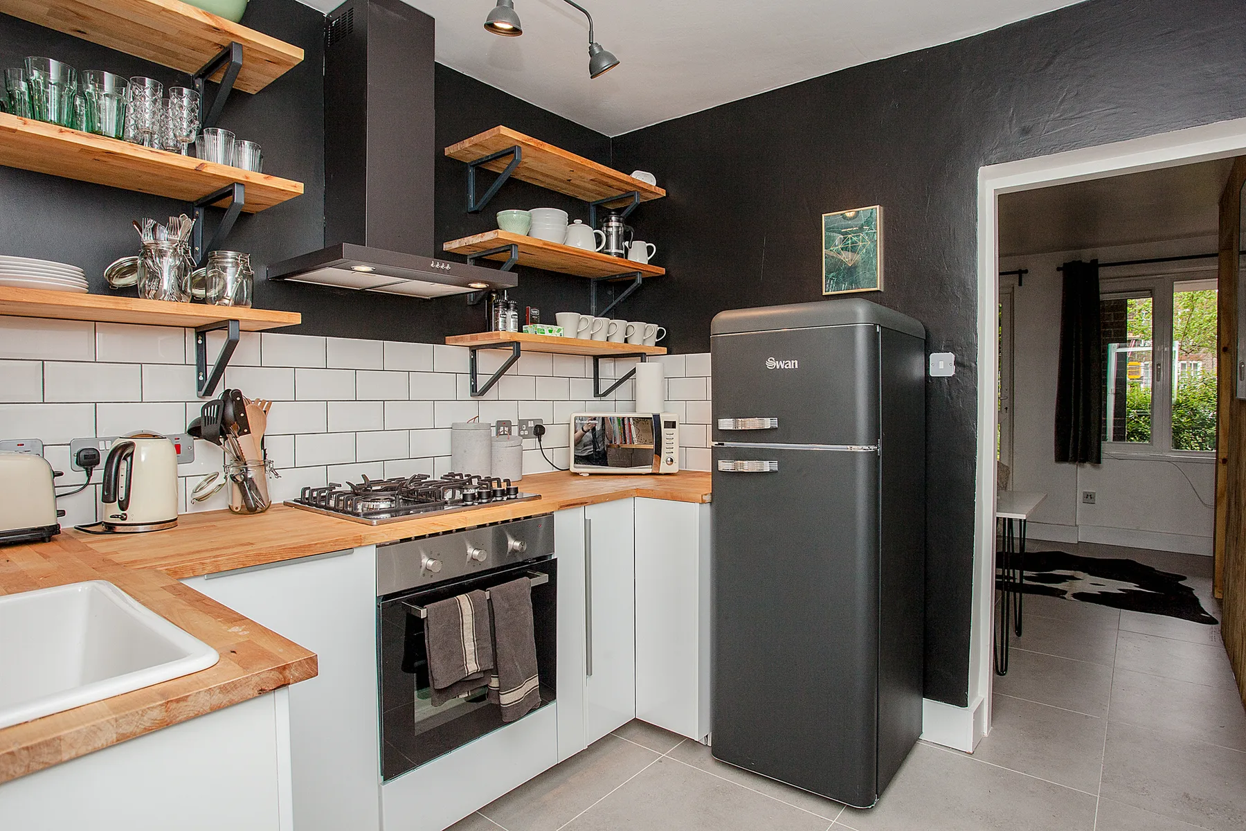 A kitchen with wooden countertops, white cabinets, and dark walls.