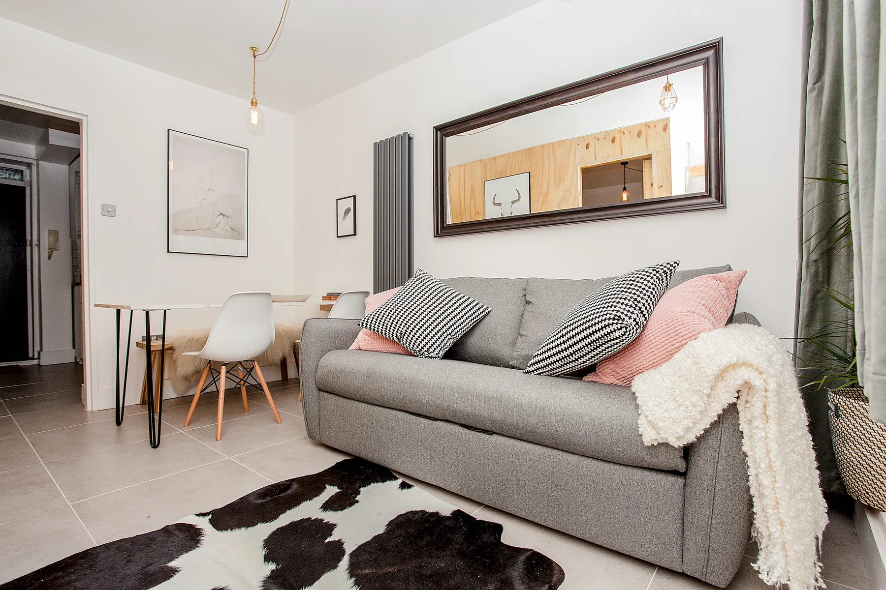 A living room with a gray sofa, dining table, and patterned rug.