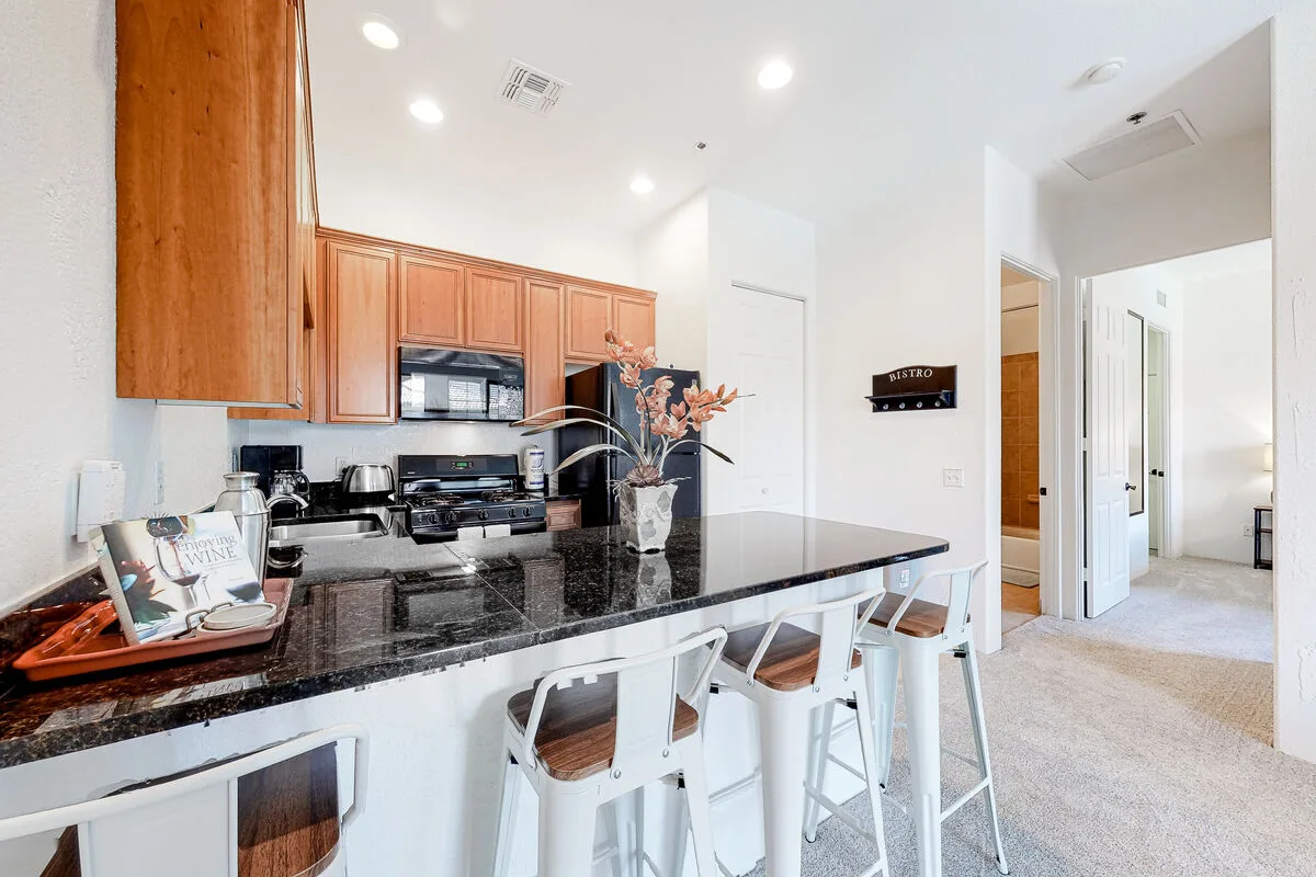 Una cocina luminosa con gabinetes de madera y una encimera oscura.