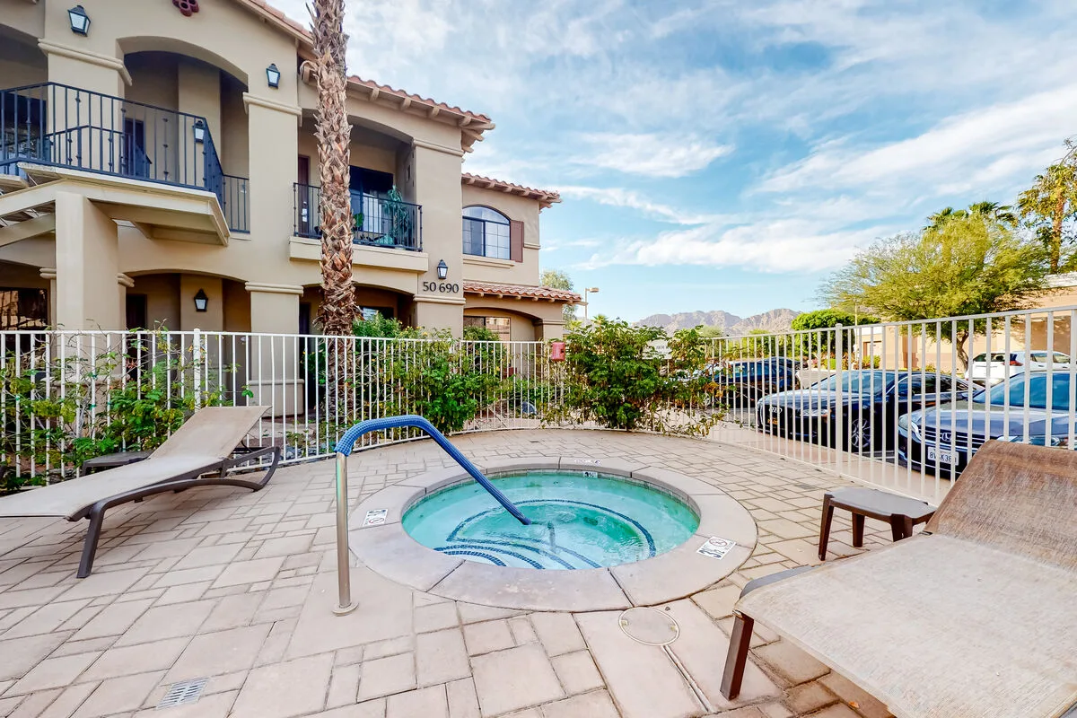 Un patio al aire libre con una pequeña piscina circular, asientos y una cerca alrededor.