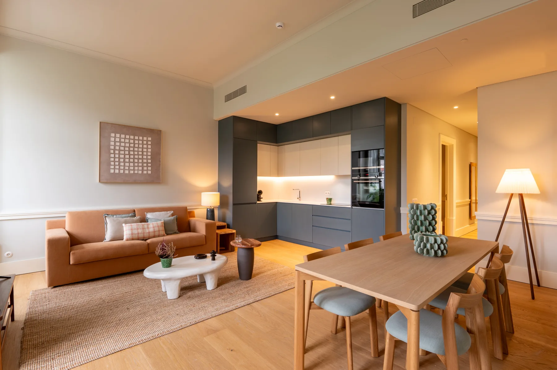 An open-plan living and dining area with a kitchen and sofa.