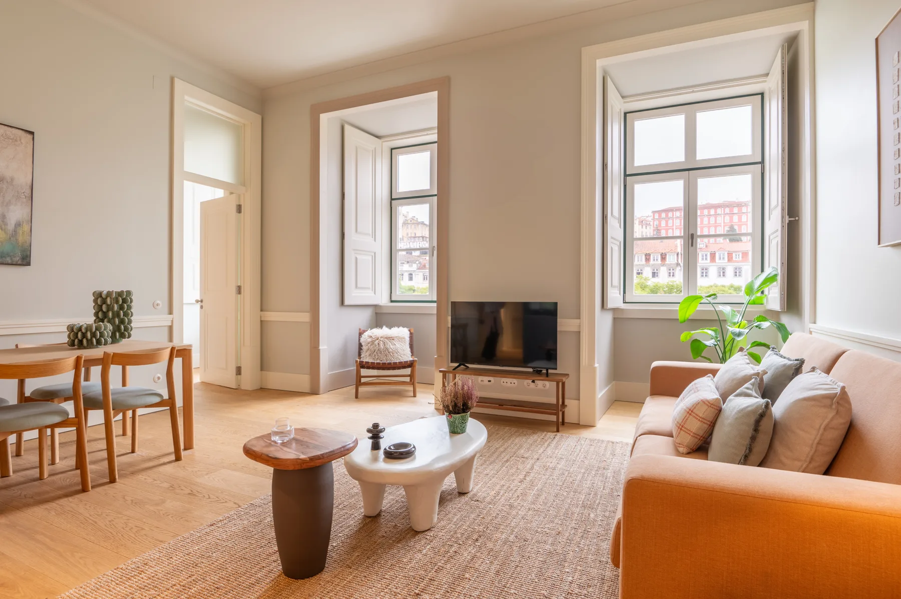 A bright living room with seating, a coffee table, and large windows.