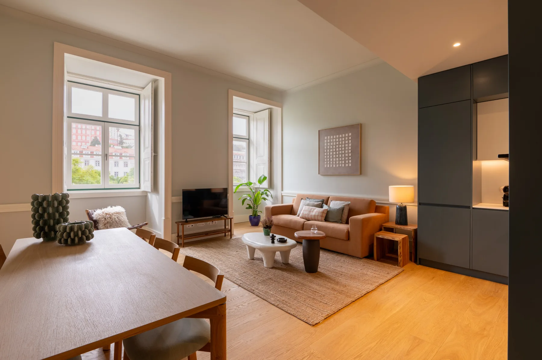 A living and dining area with seating, a coffee table, and tall windows.