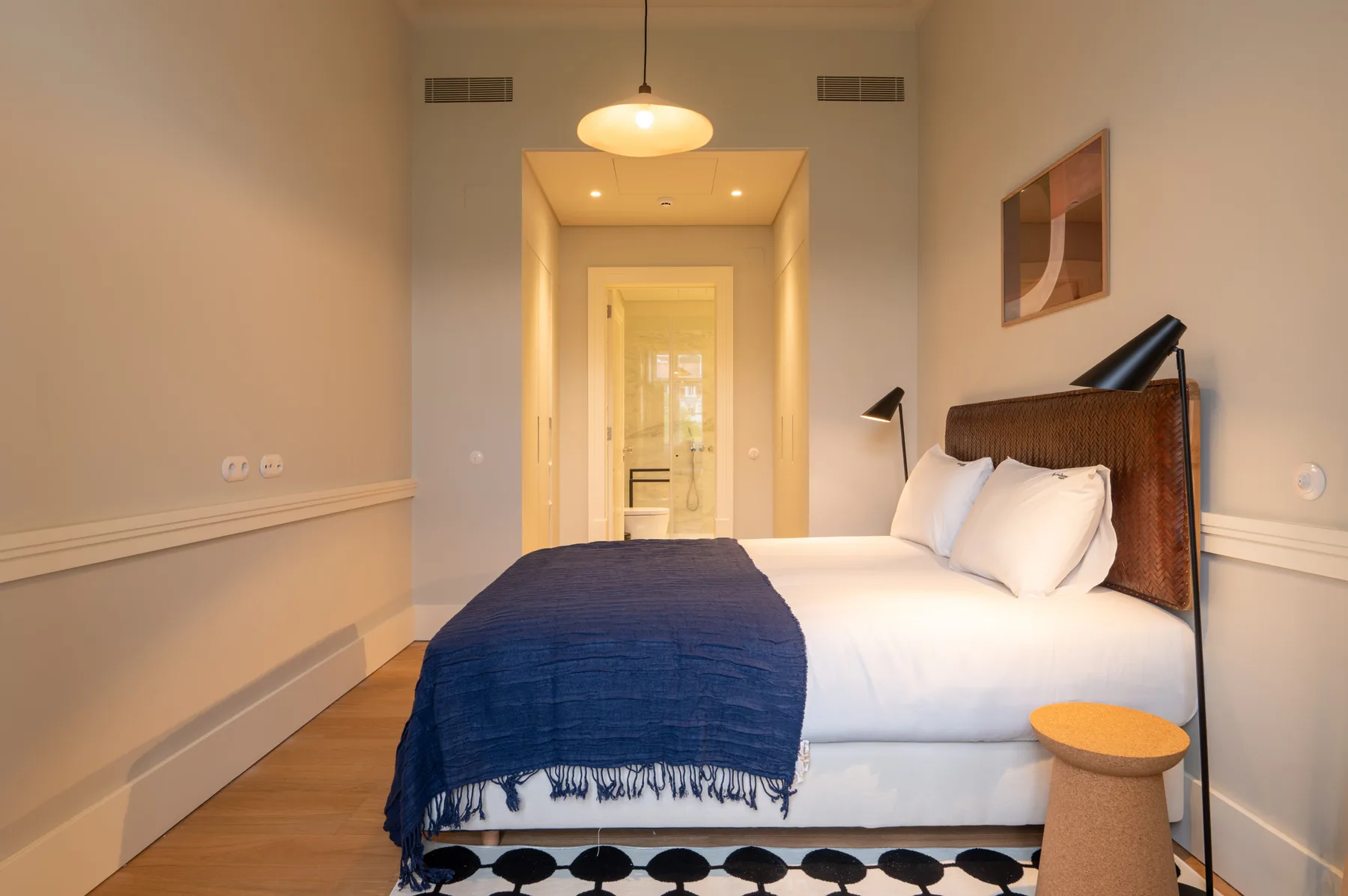 A bedroom with a bed dressed in white linens and a blue throw.