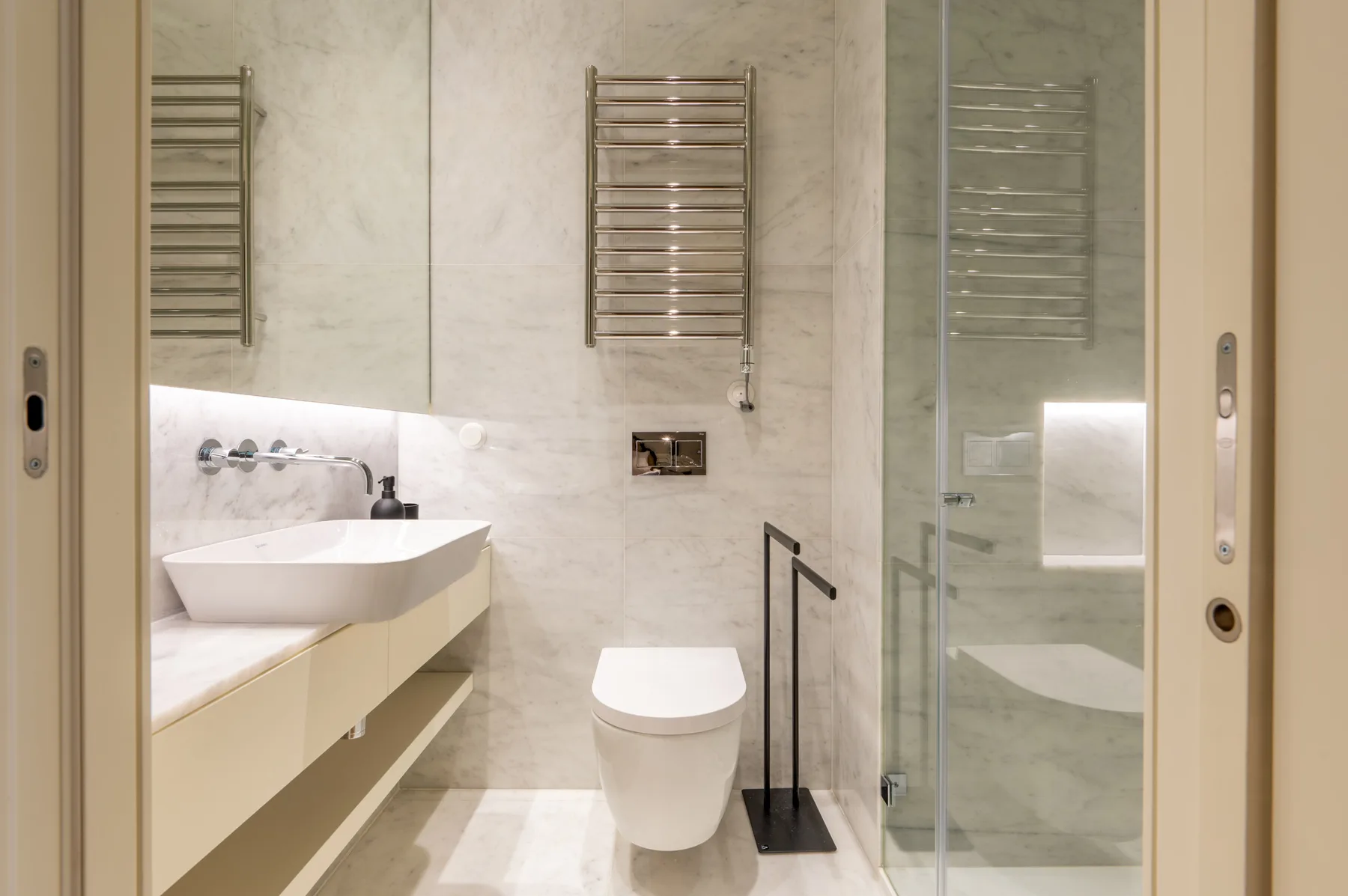 A bright bathroom with a wall-mounted sink and glass shower.