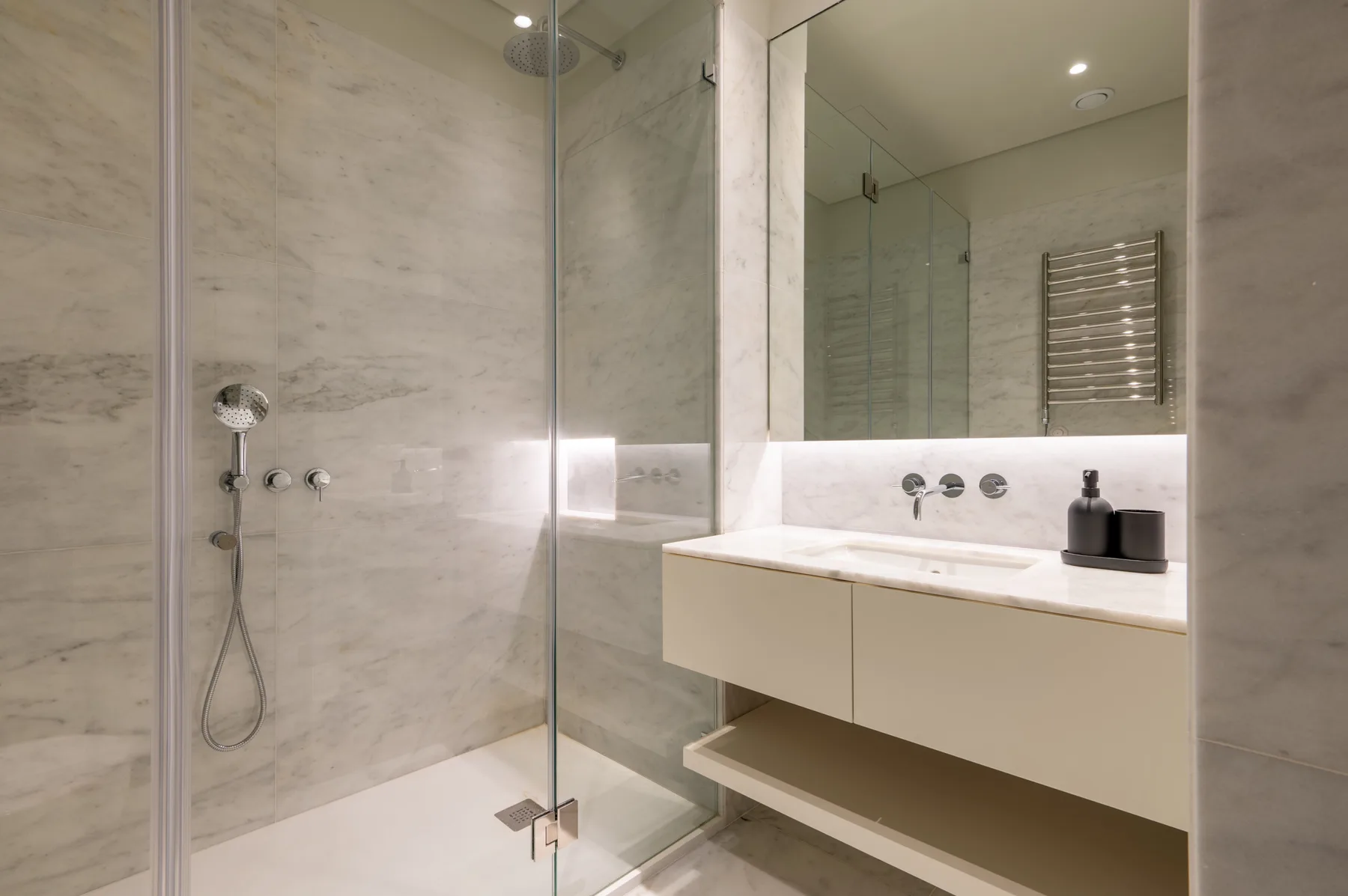 A bathroom with a glass shower and a floating vanity beneath a large mirror.