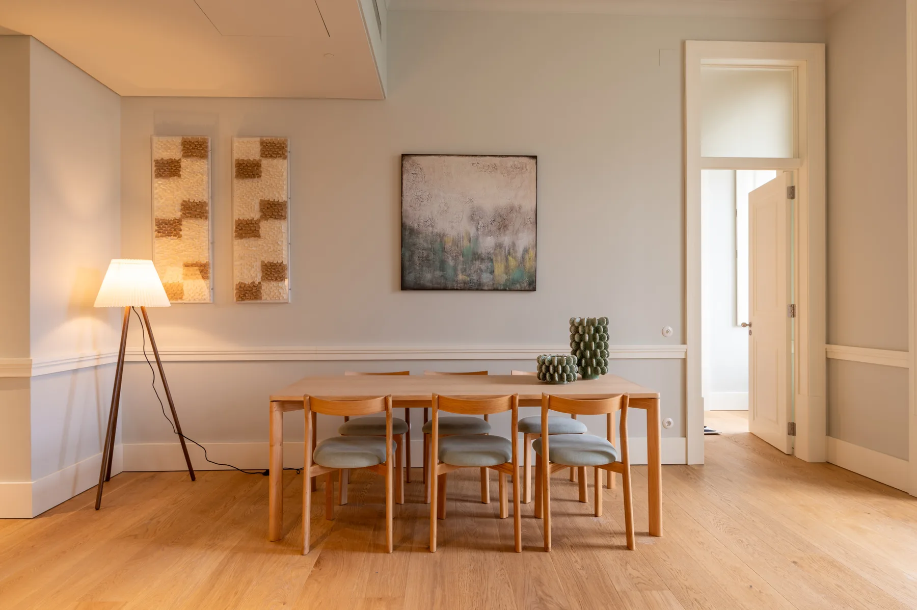 A dining area with a wooden table, chairs, and framed artwork on the wall.