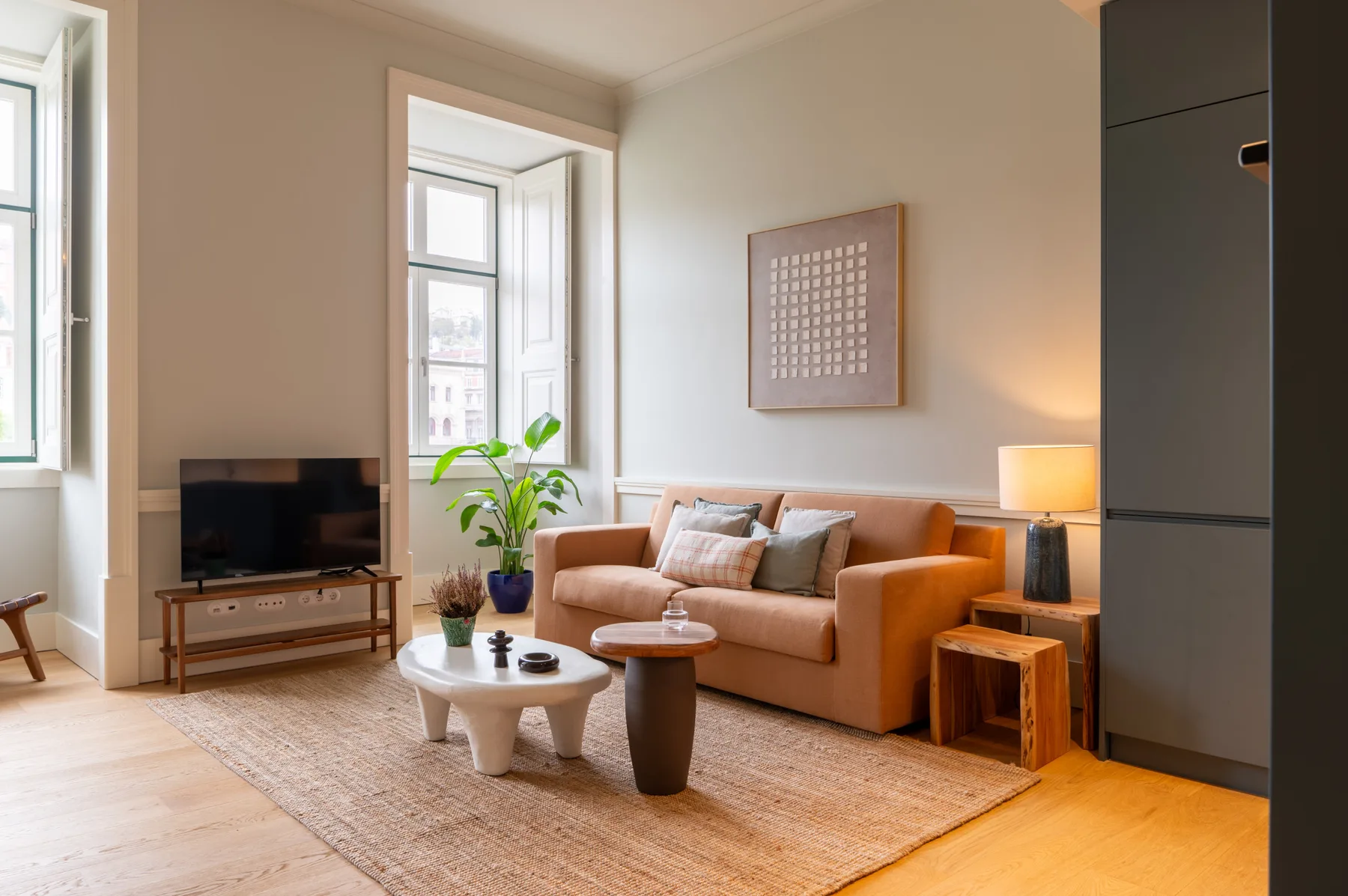 Living room with a sofa, television, and large windows.