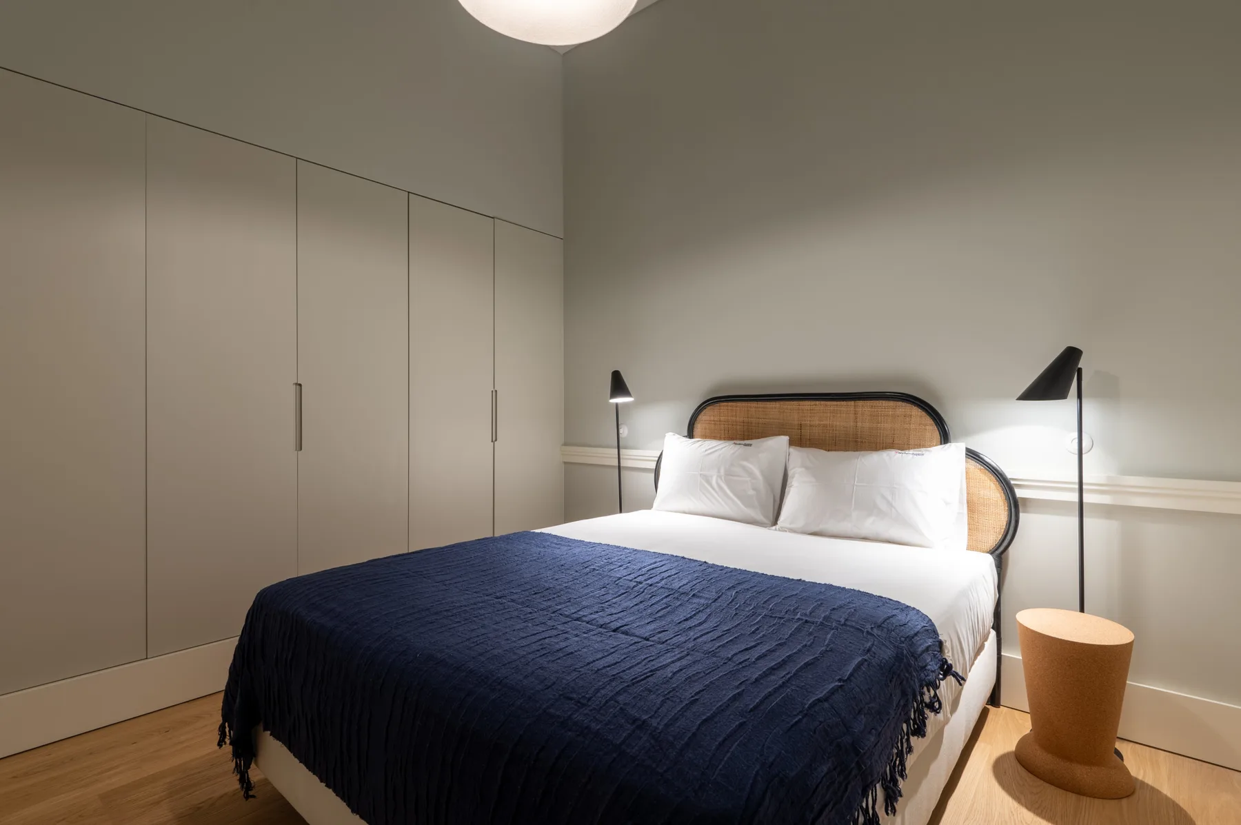 A bedroom with a bed covered by a dark blue blanket.