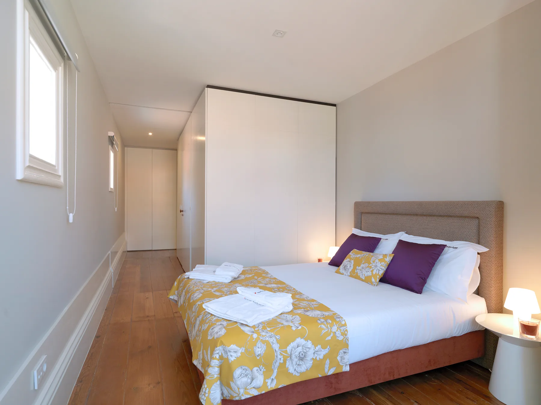 A bright bedroom with a double bed and yellow floral bedding.