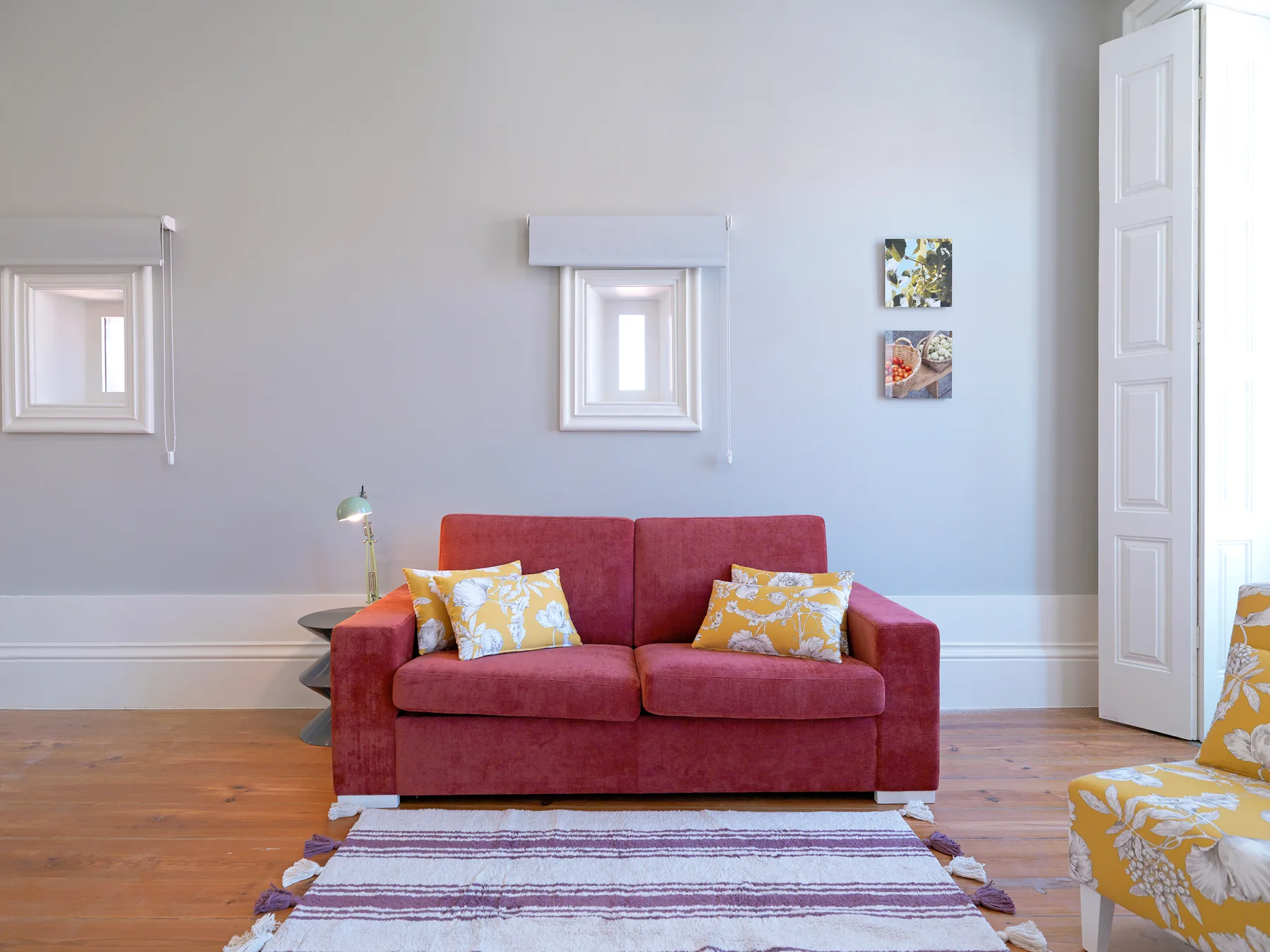 A red sofa sits against a pale wall in a bright living room.