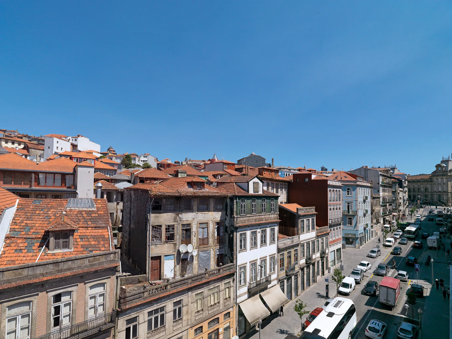 A cityscape of closely packed buildings with red-tiled roofs along a street.