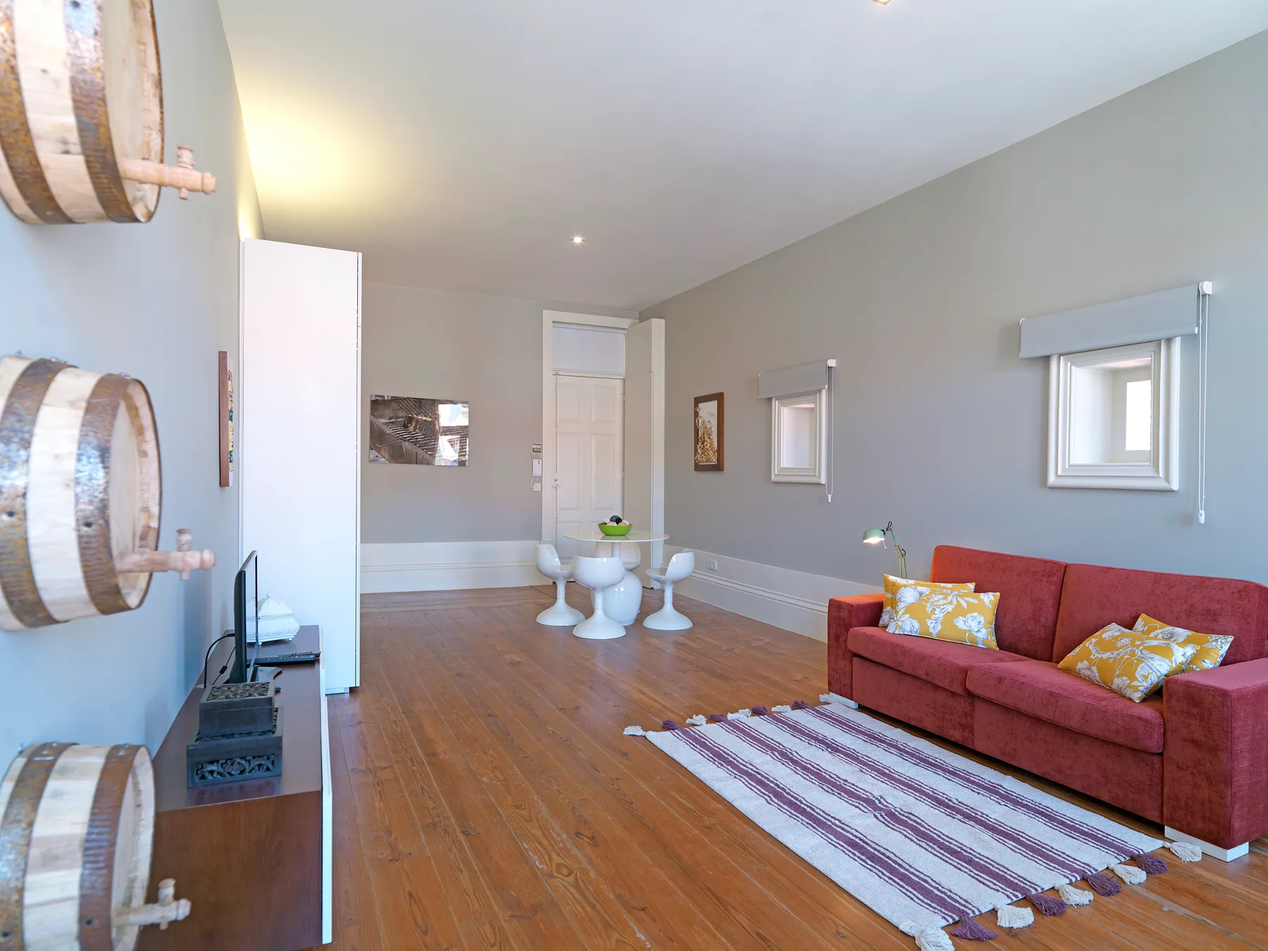 A living room with red seating, small windows, and a striped rug.