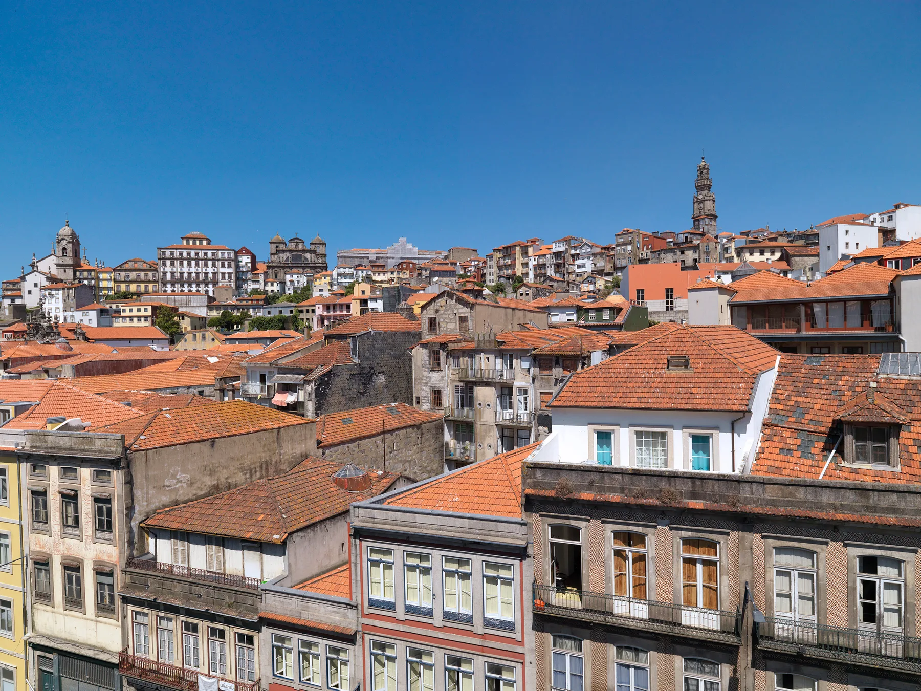 A cityscape of Porto’s historic center, with dense buildings and red-tiled roofs.