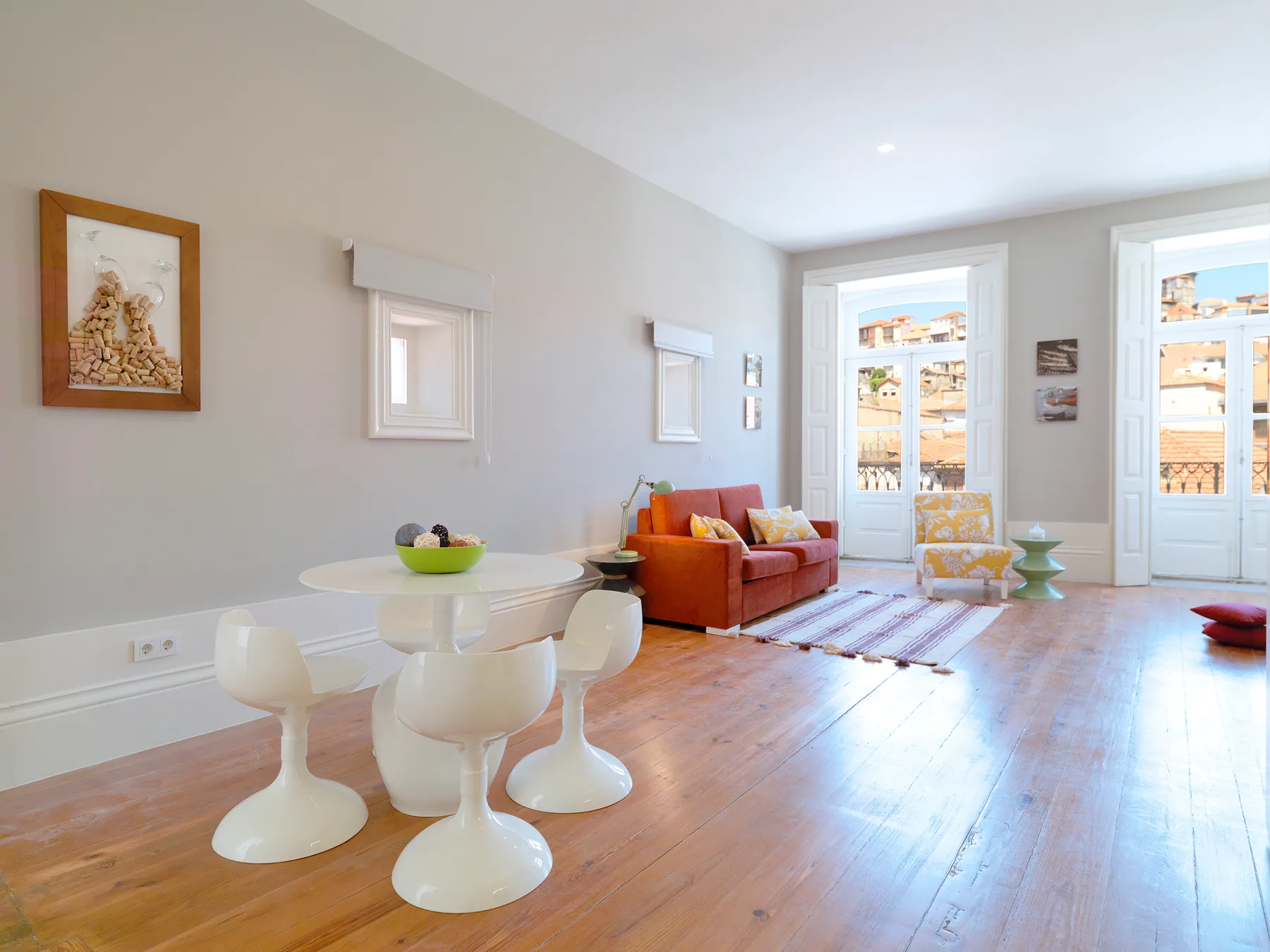 A bright living room with a dining table, seating, and tall windows.