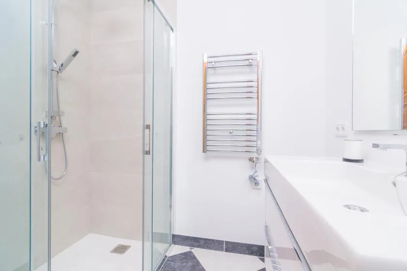A bright bathroom with a glass shower and a long white countertop.