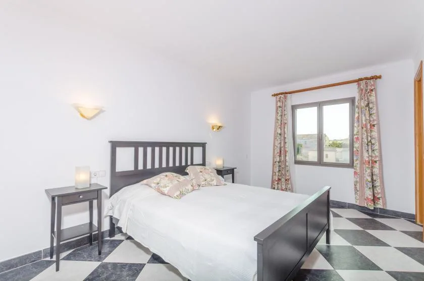 A bedroom with a bed, bedside tables, and a window with patterned curtains.