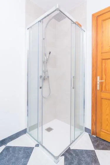 A shower with clear glass panels stands beside a wooden door.