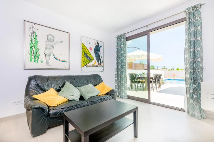 A living room with a dark sofa and a sliding glass door opening onto a patio.