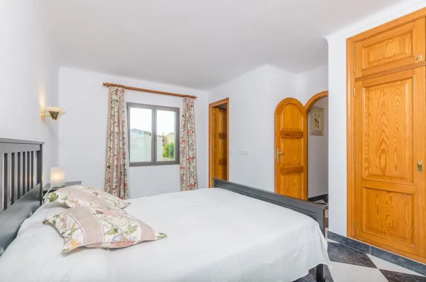 A bedroom with a large bed, floral curtains, and wooden doors.
