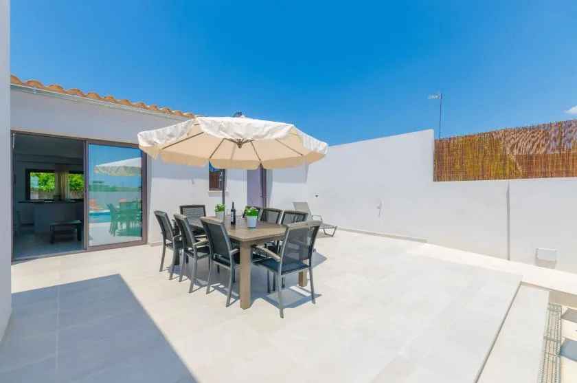 An outdoor dining area with a table and chairs beneath a large umbrella.