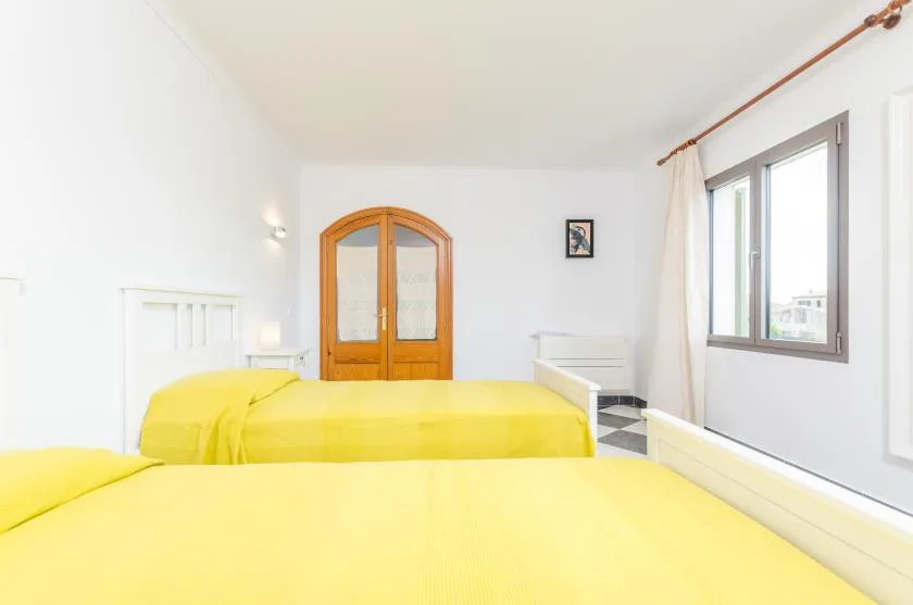 A bright bedroom with yellow bedding and a wooden wardrobe.