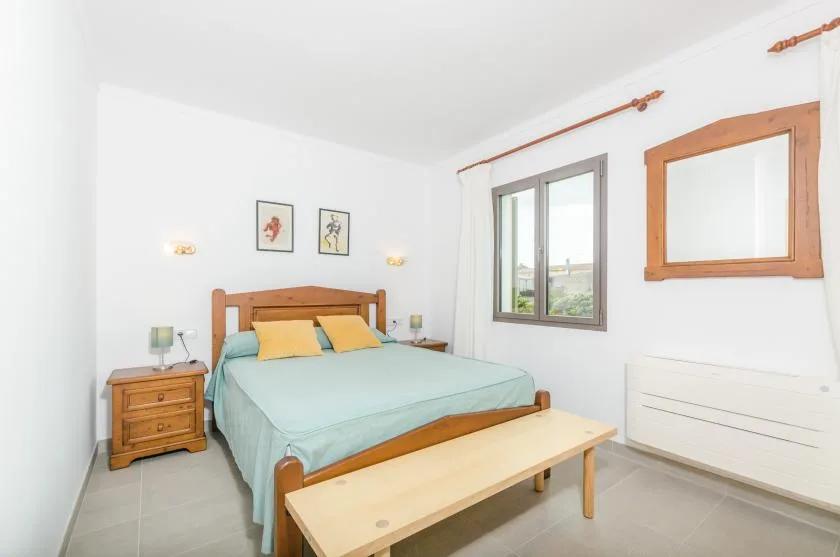 A bright bedroom with a wooden bed and a window.
