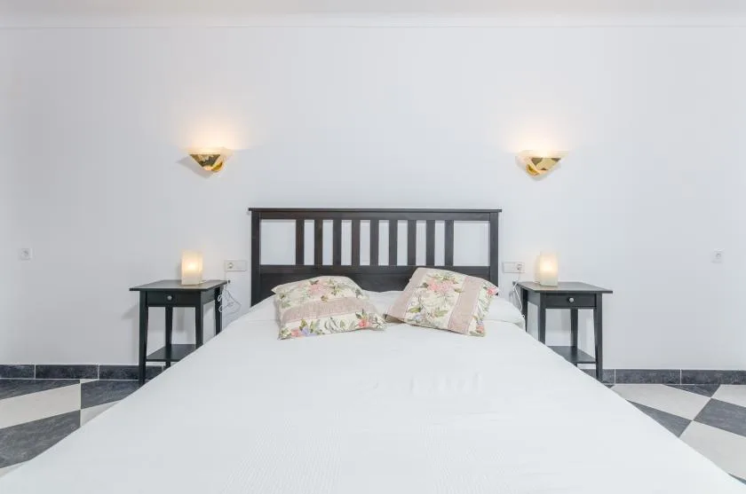 A bedroom with a bed, floral pillows, and matching bedside tables.