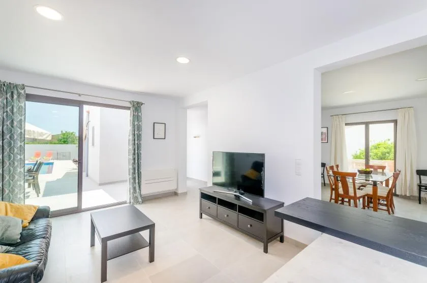 A bright living room opens onto a patio, with a television and dining area nearby.