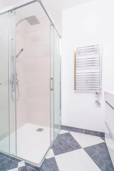 A bright bathroom with a glass shower and a wall-mounted towel warmer.