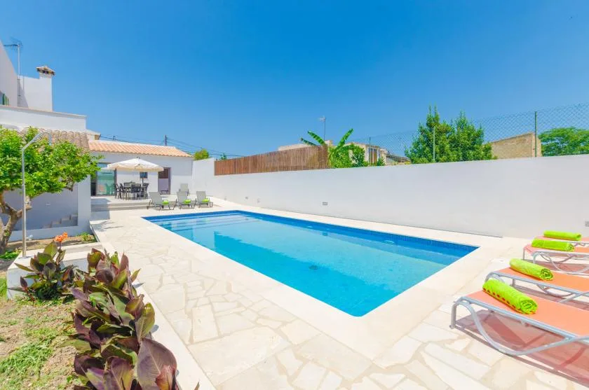 An outdoor swimming pool with lounge seating beside a bright patio.