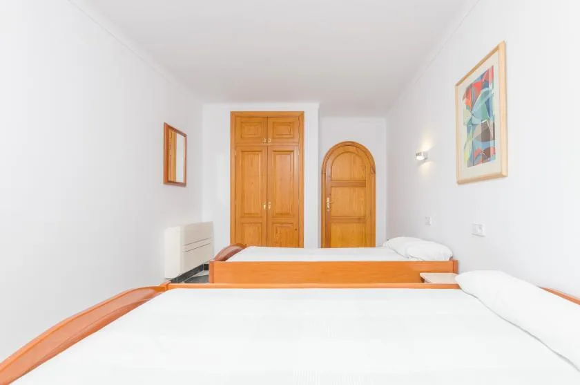 A bright bedroom with white beds and wooden doors.
