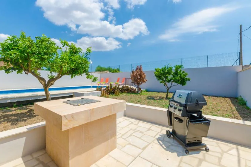 A paved outdoor patio has a built-in counter and a barbecue grill.