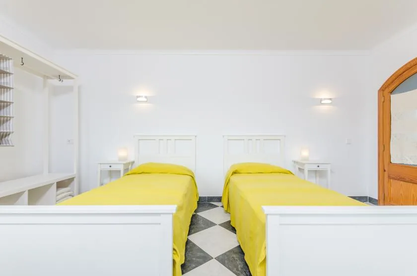 A bright bedroom with two beds covered in yellow bedding.