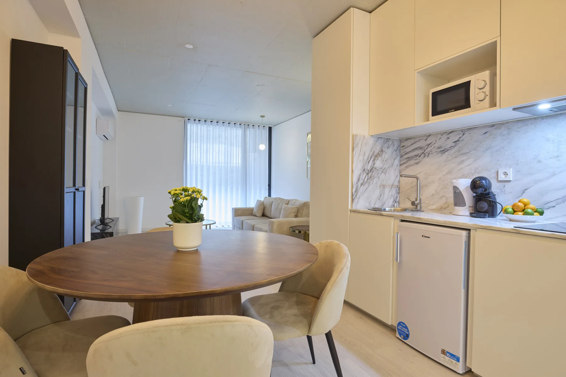 A dining area beside a compact kitchen, with a round table and seating.