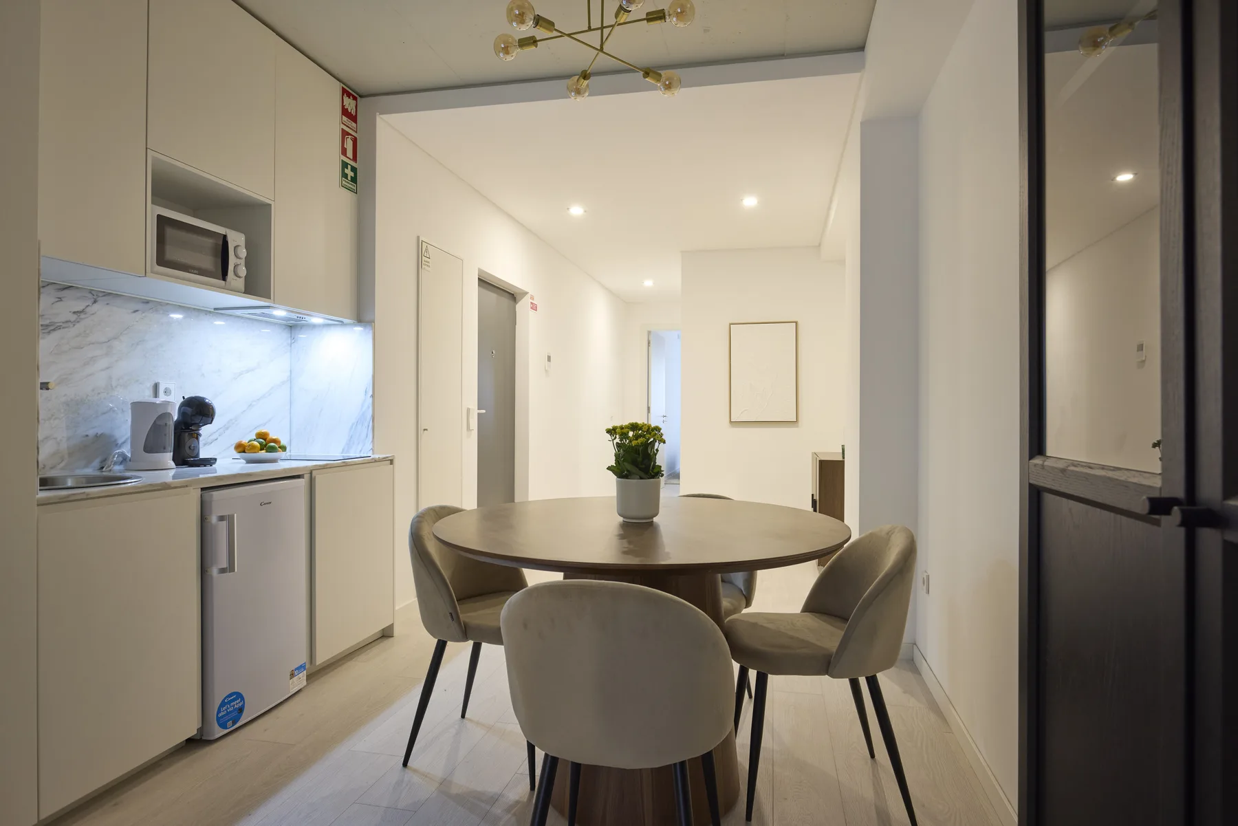 A dining area with a round table and seating beside a compact kitchen.