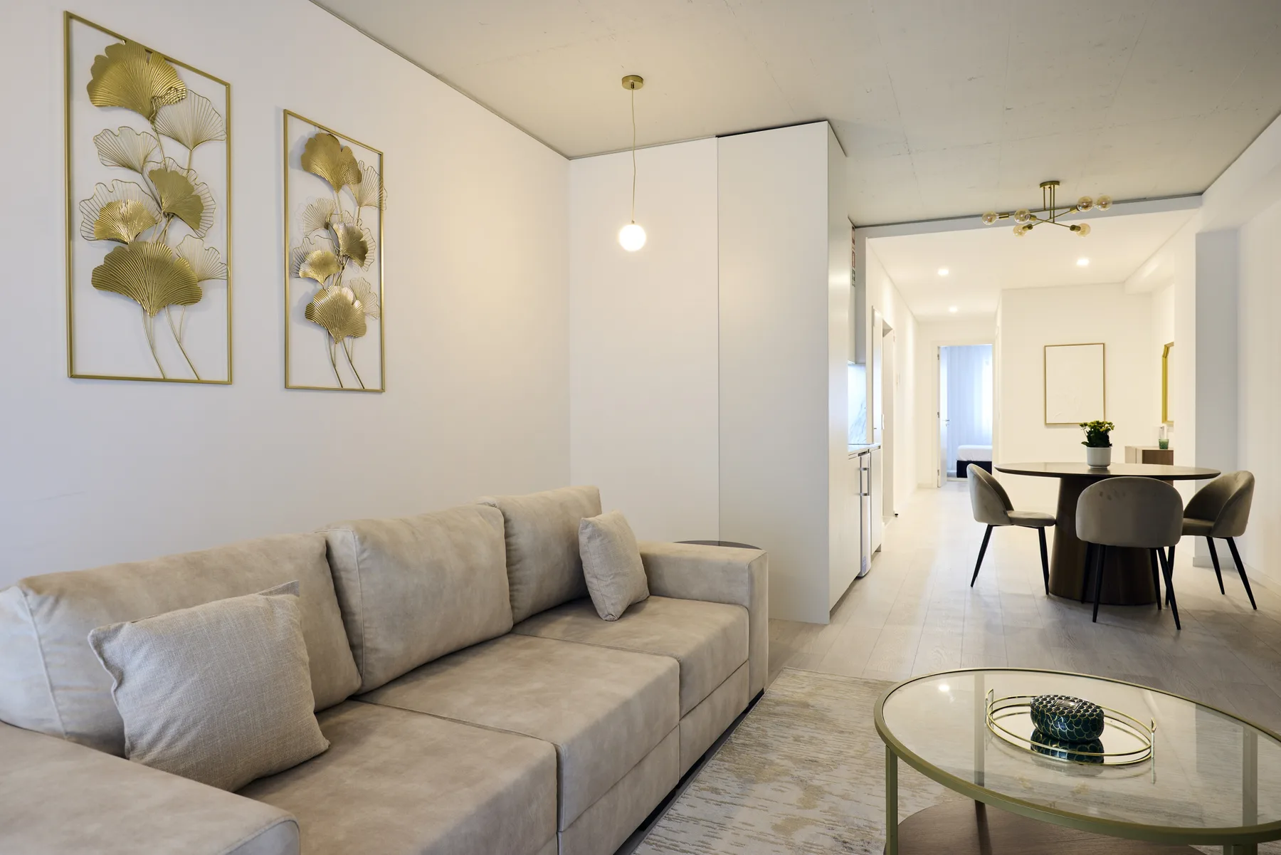 A bright living room with a sofa and a dining area beyond.