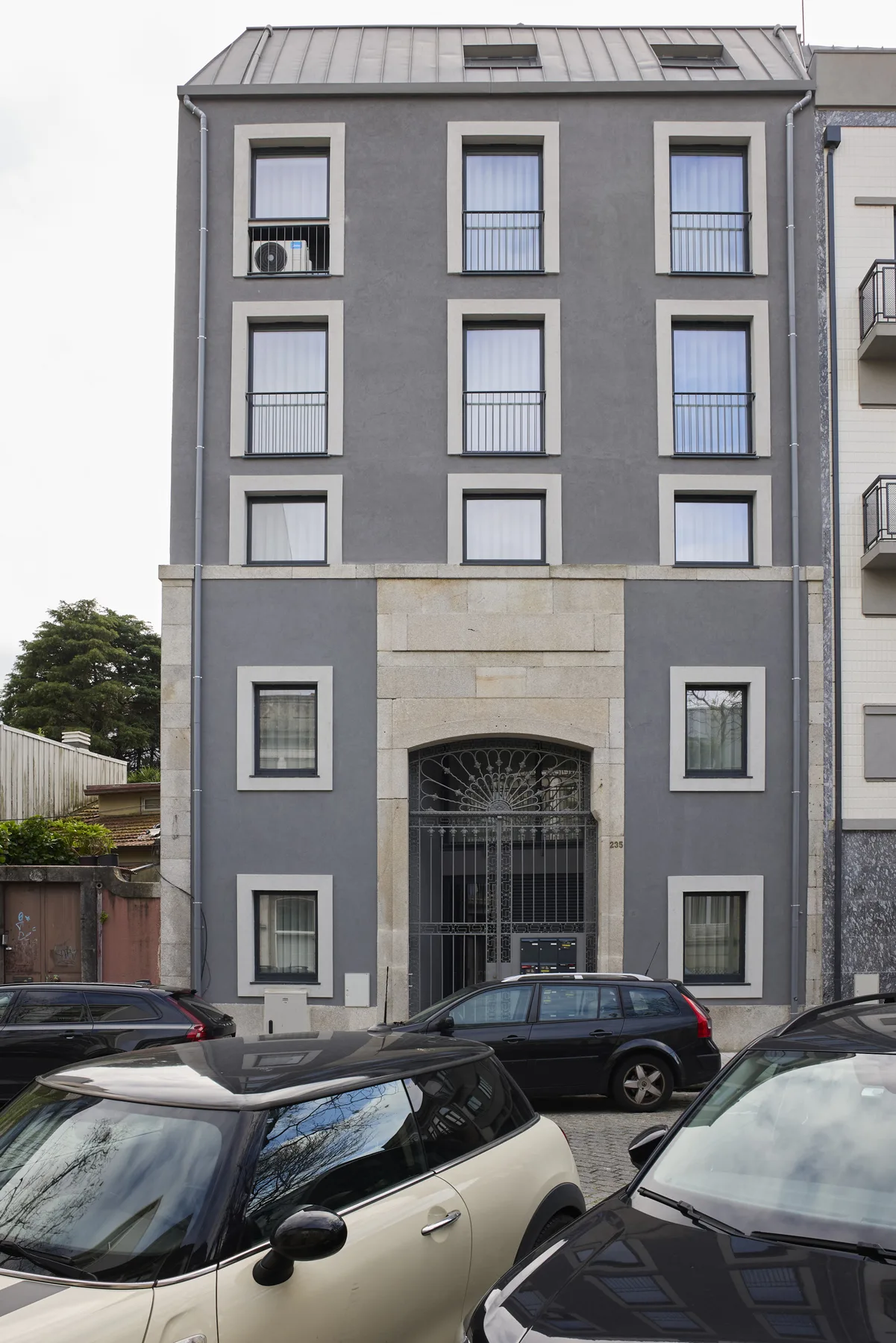 A gray apartment building with rows of windows and a central entrance.