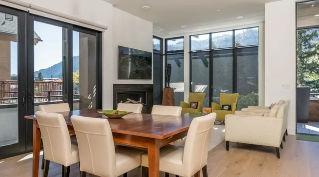 Un comedor se abre a una luminosa sala de estar con grandes ventanas.