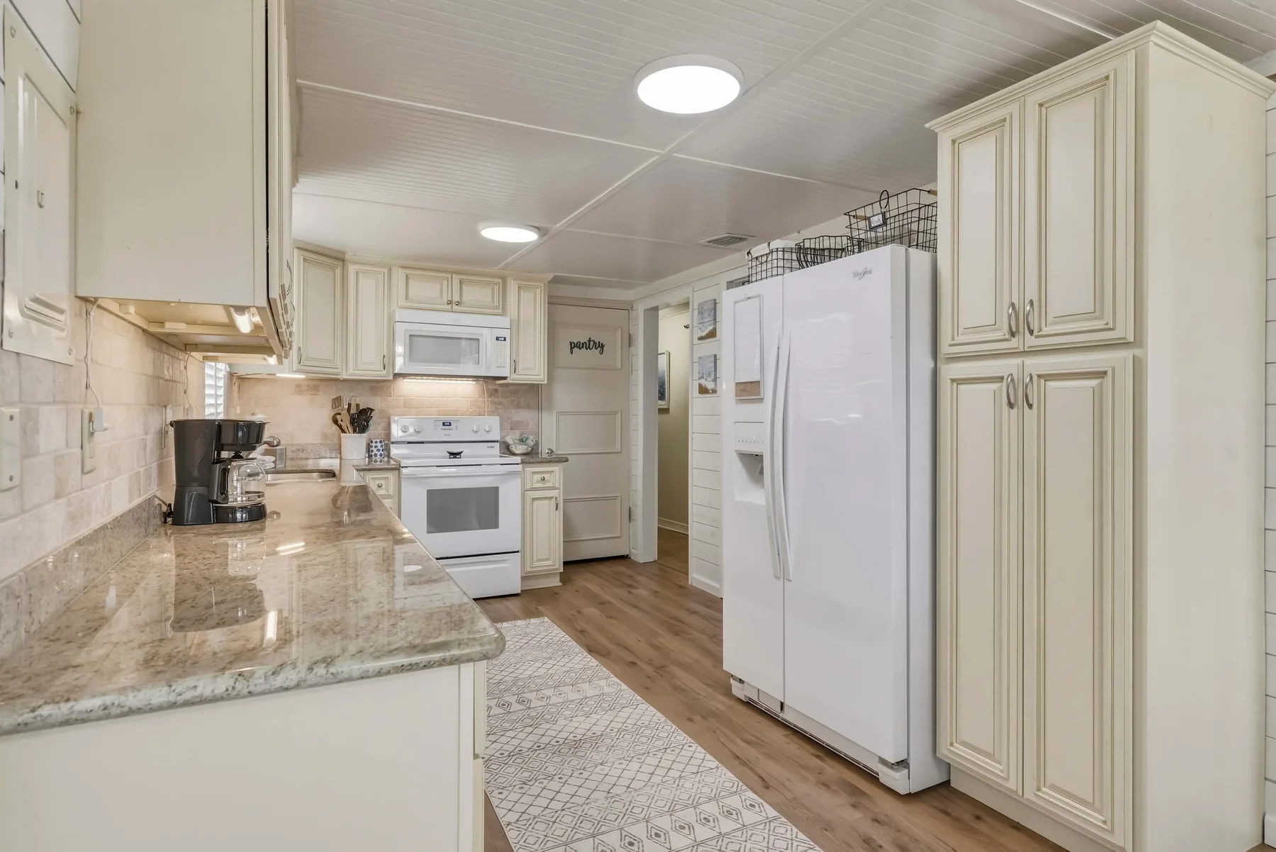 Una cocina luminosa con gabinetes color crema, una estufa y un refrigerador grande.